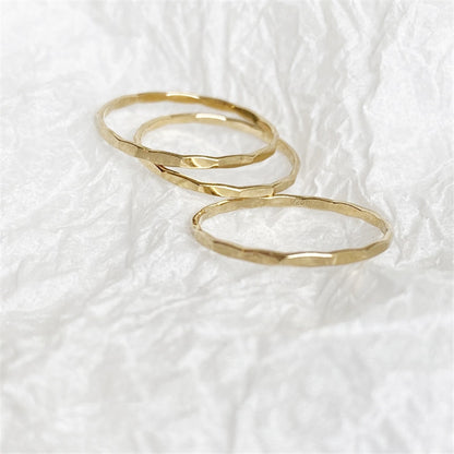 3 faceted gold rings sit gently on a white background of luxurious textured paper